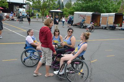 Woman in a red hoodie chats with three players in blue tank tops