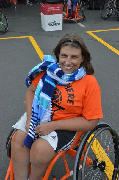 Smiling player in an orange shirt with a blue striped towel around her neck