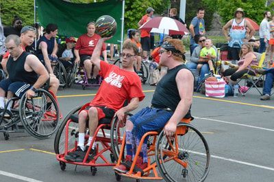 Da Burds player in red holds the ball high at Hoopfest as a defender closes in