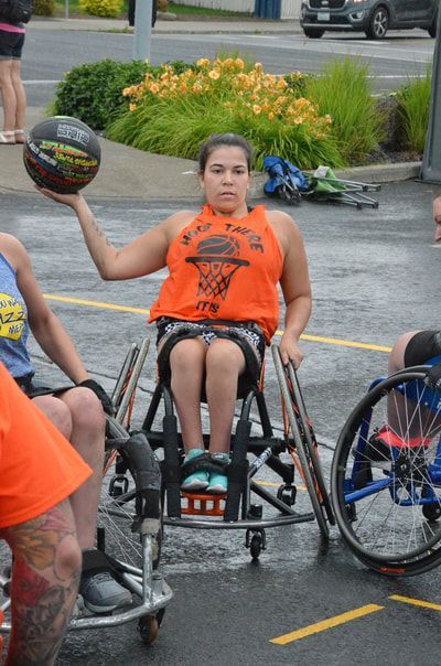 Player in an orange Hoop There It Is tank holds the ball up in one hand