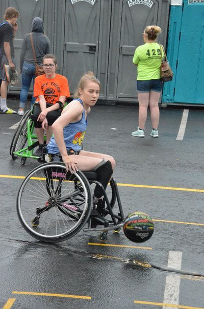 Player in a blue tank spins her wheelchair as a loose ball rolls behind her