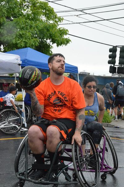 Bearded player in an orange shirt holds the ball beside his head to pass
