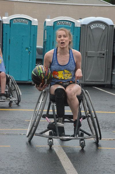 Player in a blue tank pushes toward the camera with the ball tucked at her side