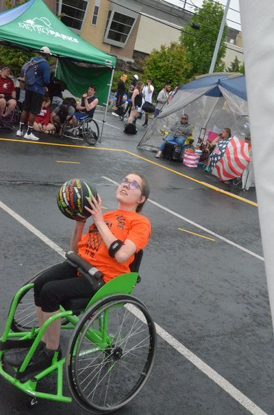Young player in an orange shirt and green wheelchair lines up a shot