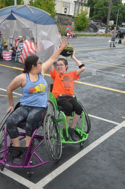 Defender in a purple wheelchair reaches up at a player in a green wheelchair