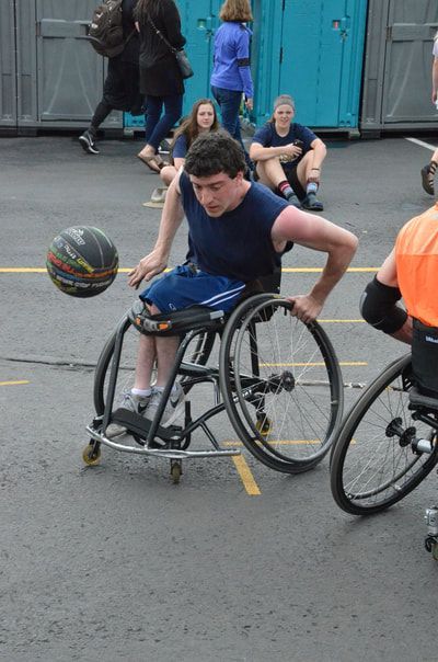 Player in a navy tank bounces the ball out in front of his wheelchair