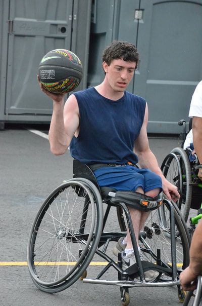 Young player in a navy tank holds the ball up in one hand, ready to pass