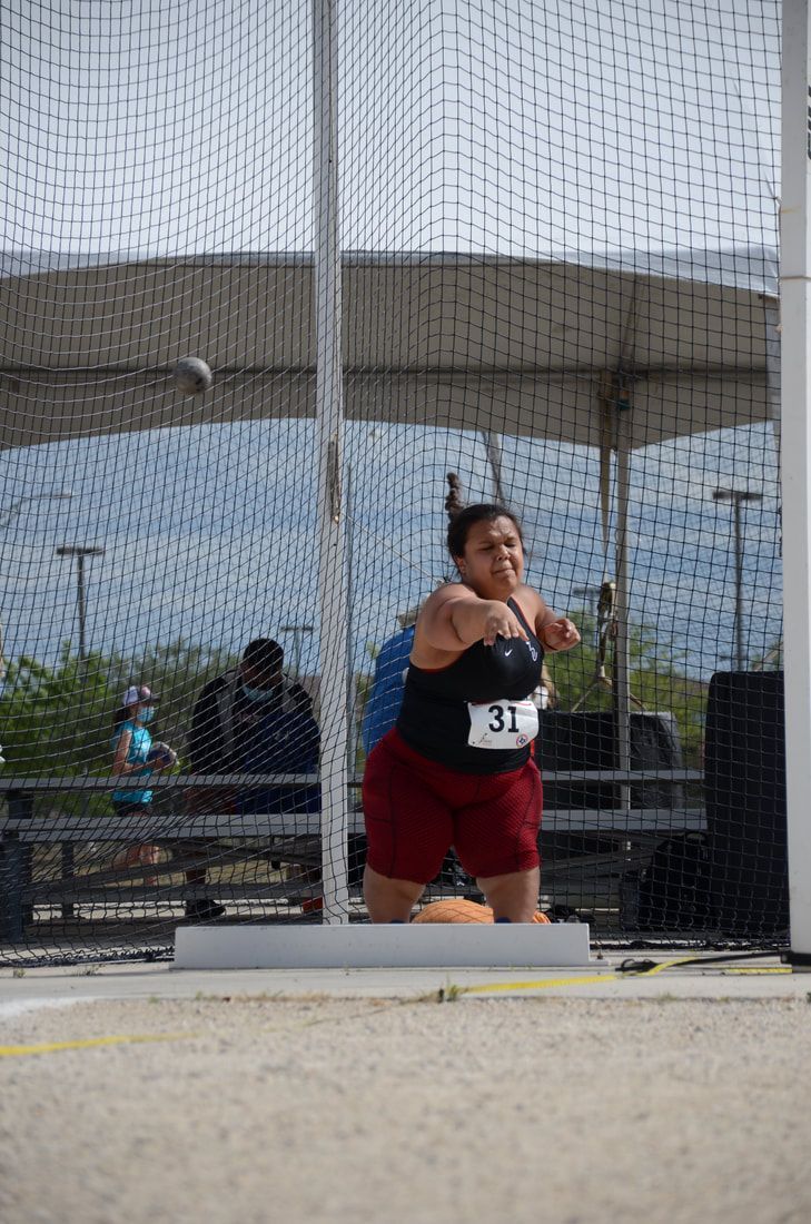 Thrower wearing bib 31 follows through as the shot flies inside the cage