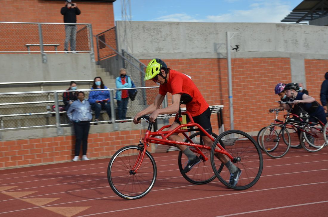 Athlete in a red shirt and yellow helmet races a RaceRunner past the stands