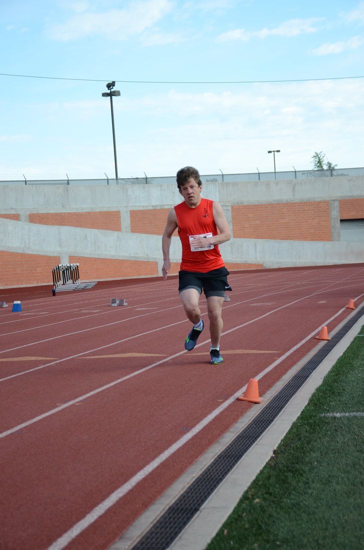 Young runner in a red top heads down the track toward the camera