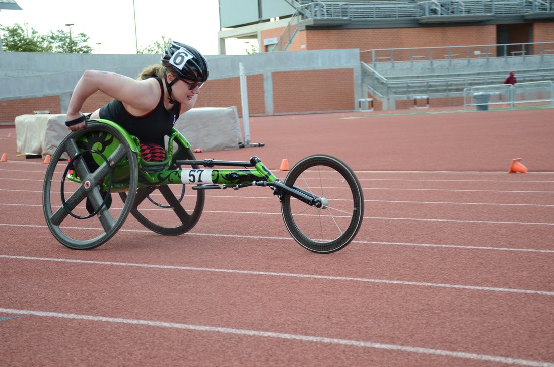 Wheelchair racer in a green racing chair, number 57, pushes down the straight