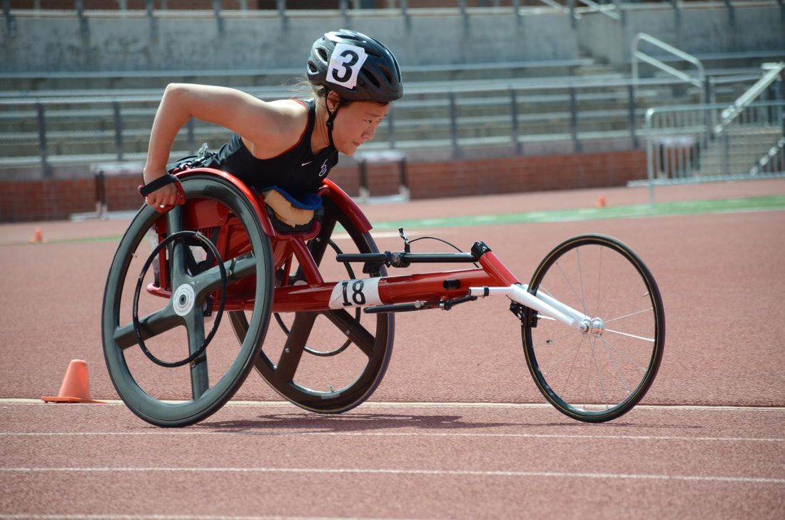 Wheelchair racer in a red racing chair, number 18, pushes along the track