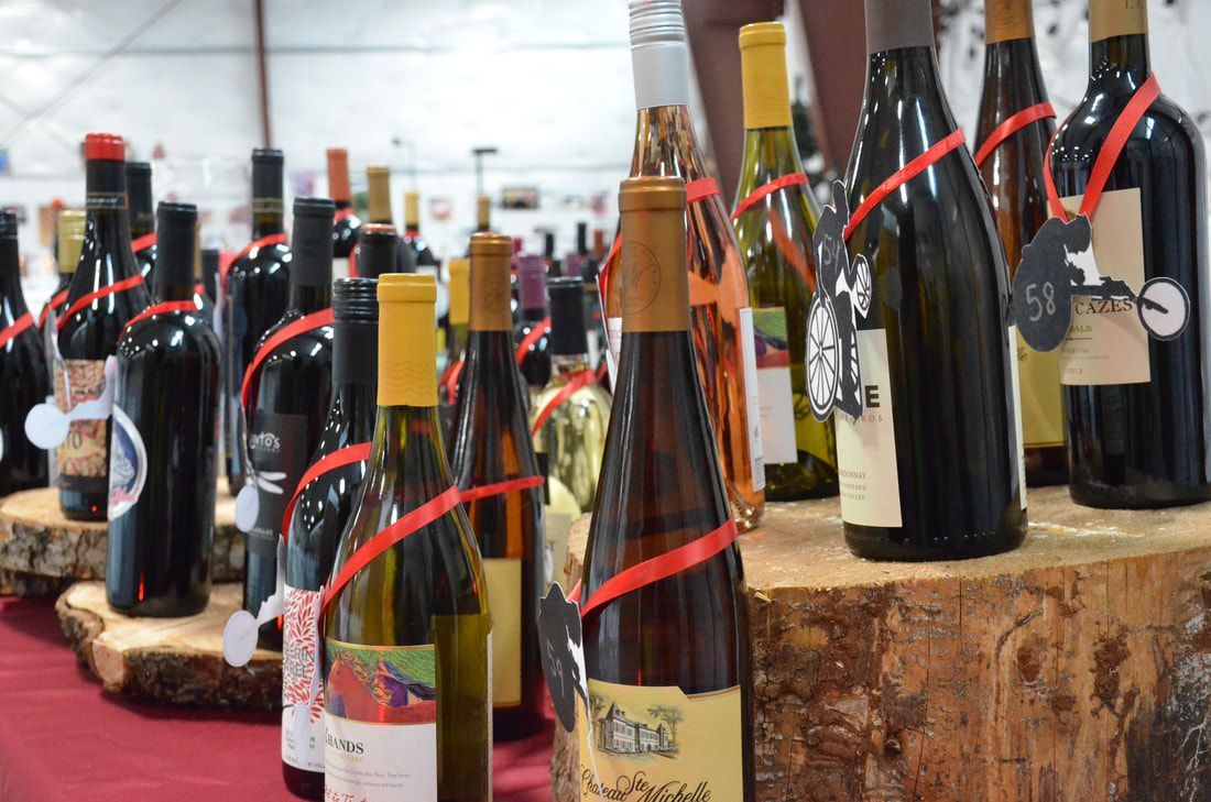 Auction wine bottles tied with red ribbons on wood slab displays
