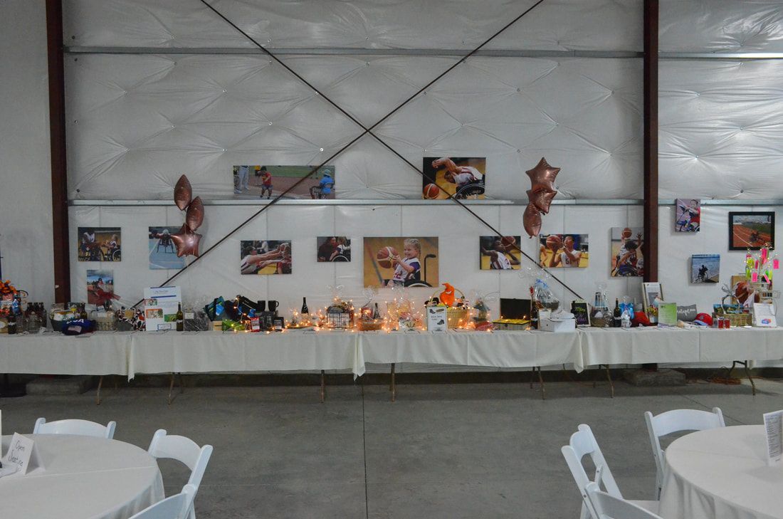 Silent auction tables beneath athlete photos in the event hall
