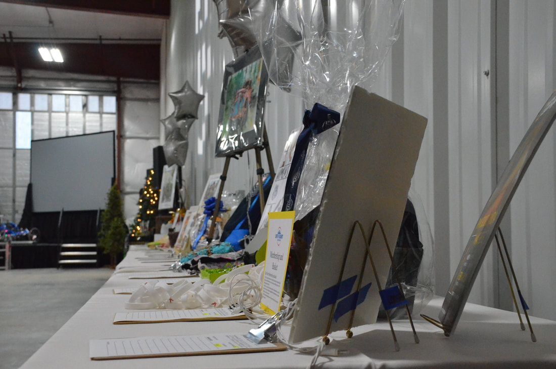 Silent auction bid sheets and items line a long table