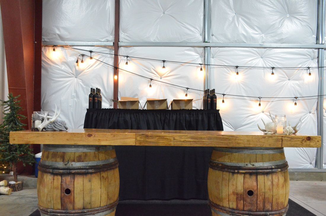Bar built from wine barrels and a wood plank under string lights