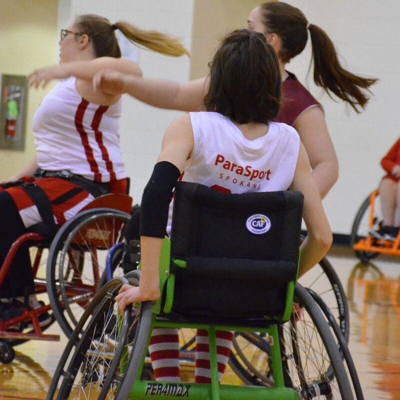 ParaSport player seen from behind as teammates reach high during a game