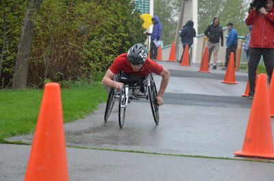 Racer in red pushes through a coned course on a wet path