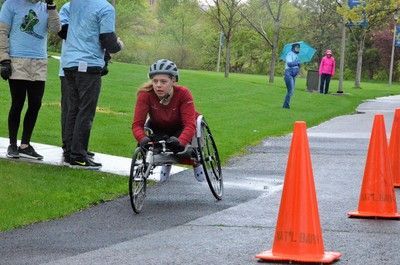 Racer in a red top rounds a coned path as volunteers watch