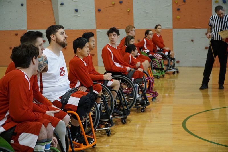 Players in red warm-ups line up courtside at the Seattle Slam