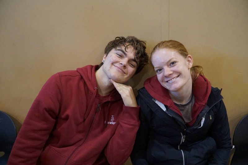 Two smiling teammates lean together, one in a maroon ParaSport hoodie