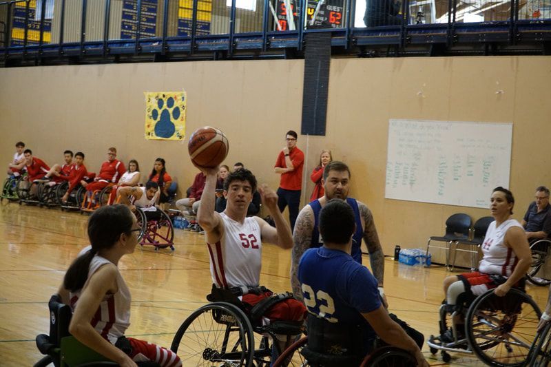 Player #52 in white lifts the ball to pass as a defender in blue closes in