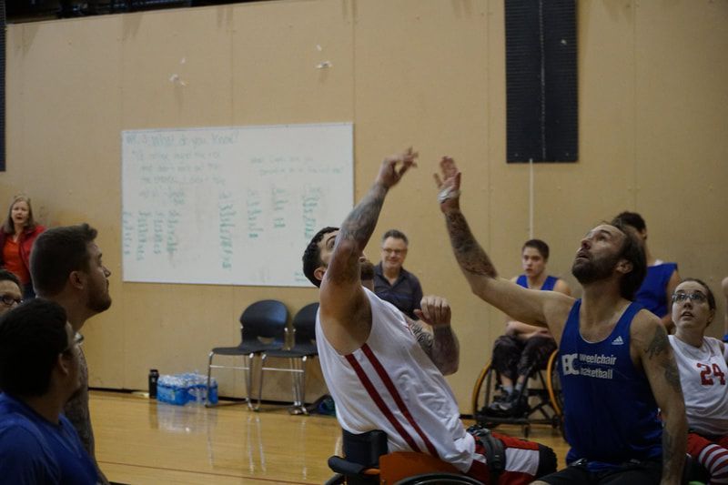 Players in white and blue reach up for a rebound under the basket