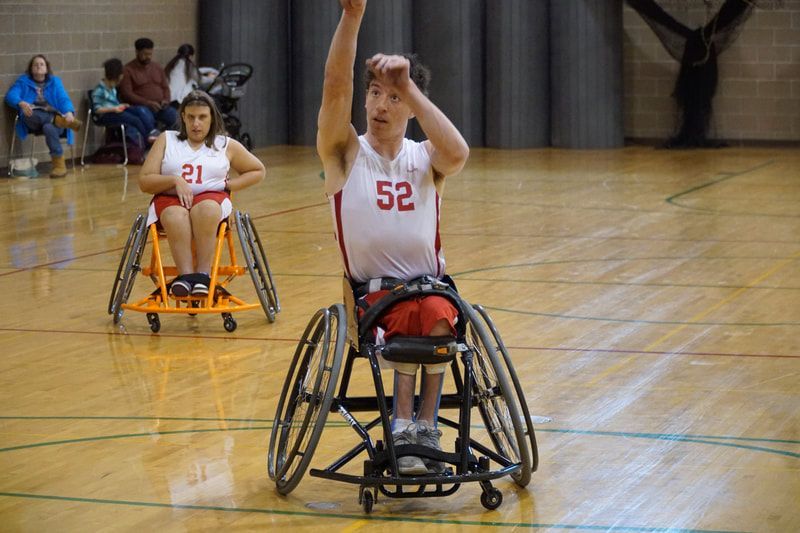 Player #52 in white raises an arm for the ball as a teammate rolls behind