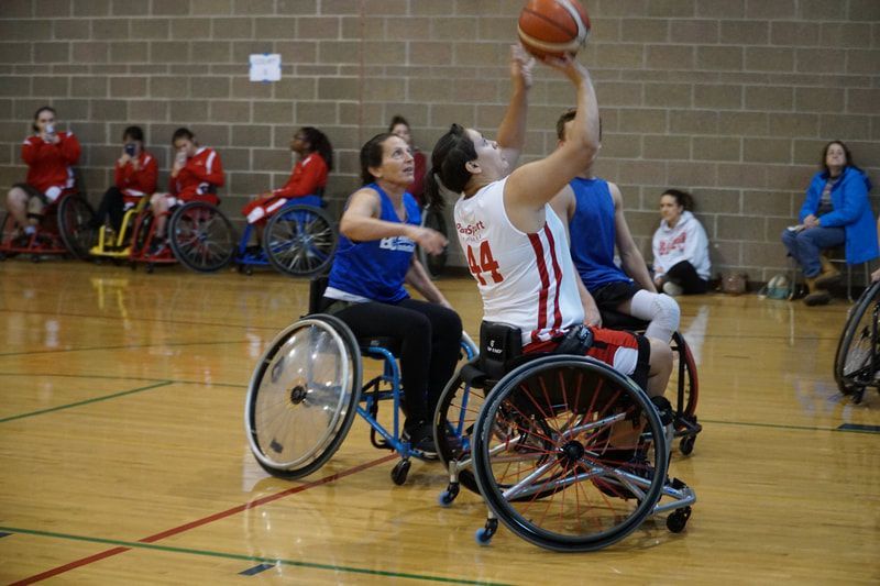 Player #44 in white shoots over a defender in blue