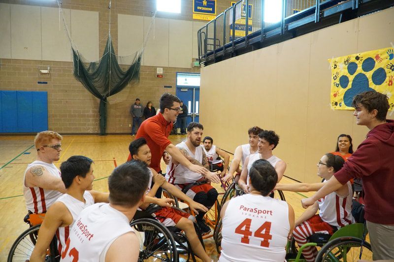 Coach in red talks to players in white jerseys during a team huddle