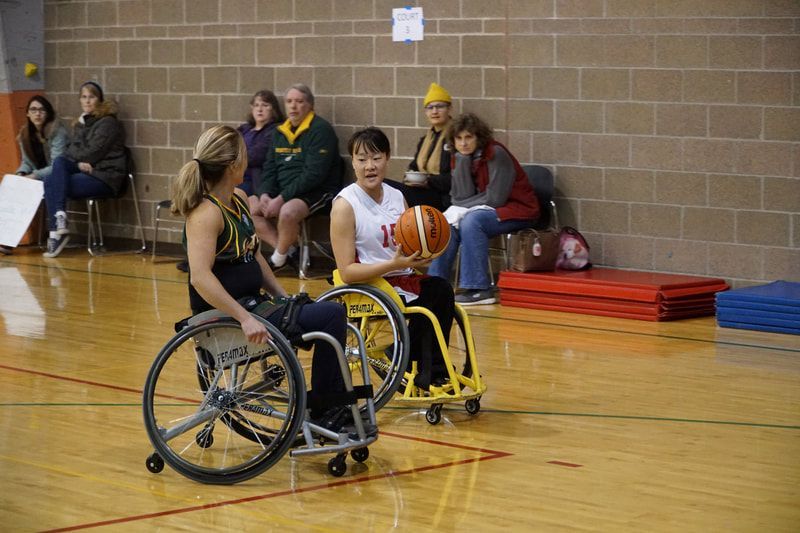 Player #15 in white looks to pass while a defender in green guards her