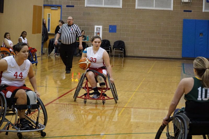 Player #33 in white pushes the ball up court with the referee behind