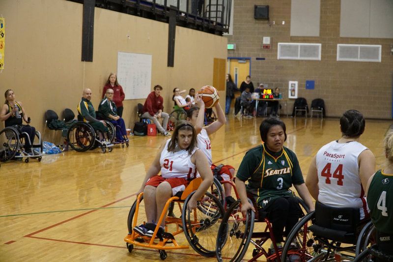 Player in white lifts the ball overhead as Seattle players in green defend