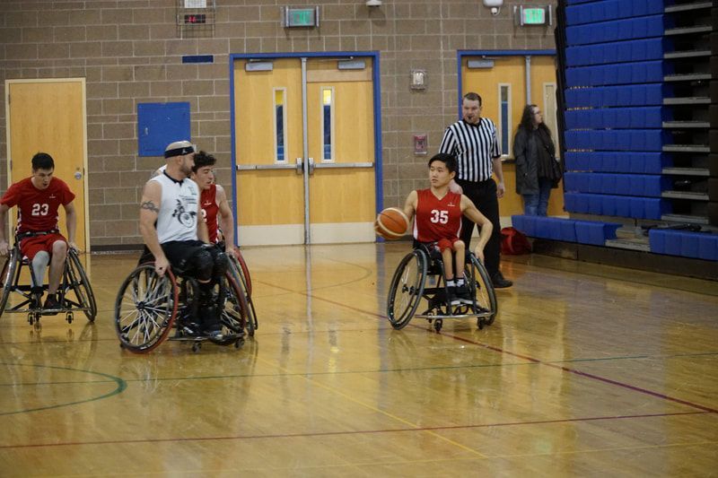 Player #35 in red dribbles up court past a defender in white