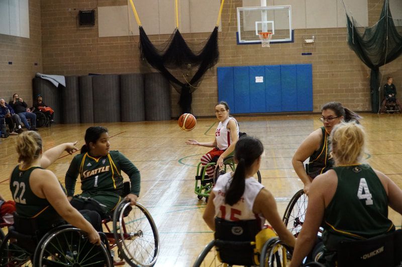 Players in white and green watch a loose ball in the air at midcourt