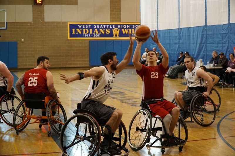 Player #23 in red shoots over a defender under a West Seattle High banner
