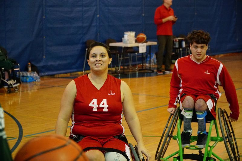Teammates in red jerseys, #44 smiling, wait on the court