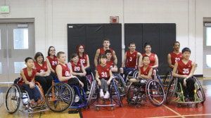 Wheelchair basketball team in red jerseys poses at the 2014 Moses Lake demo