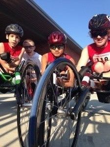 Low-angle view of young racers in helmets and racing wheelchairs