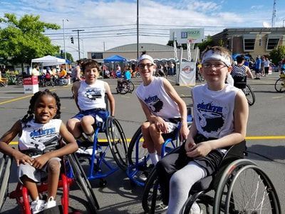 Four young players from the #Elite team pose in white jerseys at Hoopfest
