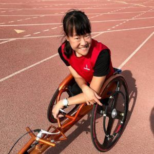 Elizabeth Floch smiles from her racing wheelchair on a track