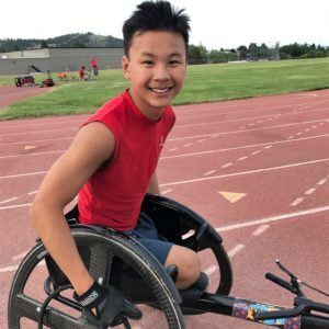 Jackson Atwood smiles in his racing wheelchair on the track