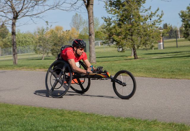 Racer in a red shirt and black helmet rolls along a park path at Bloomsday