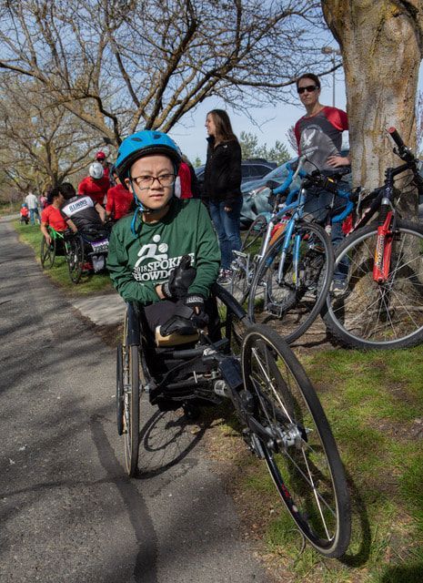 Young athlete in a blue helmet and Spokane Showdown shirt in a racing chair