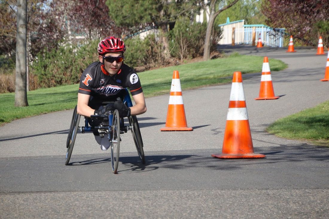 Racer in a red helmet and black jersey steers through a line of orange cones