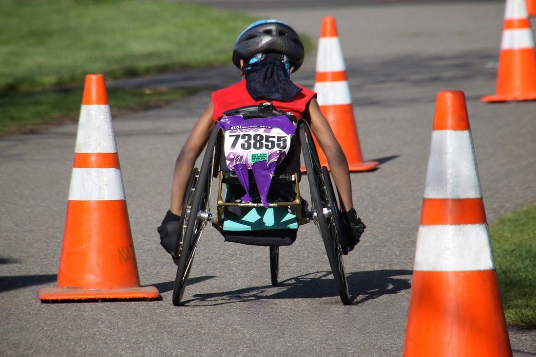 Racer wearing bib 73855 heads between orange cones, seen from behind