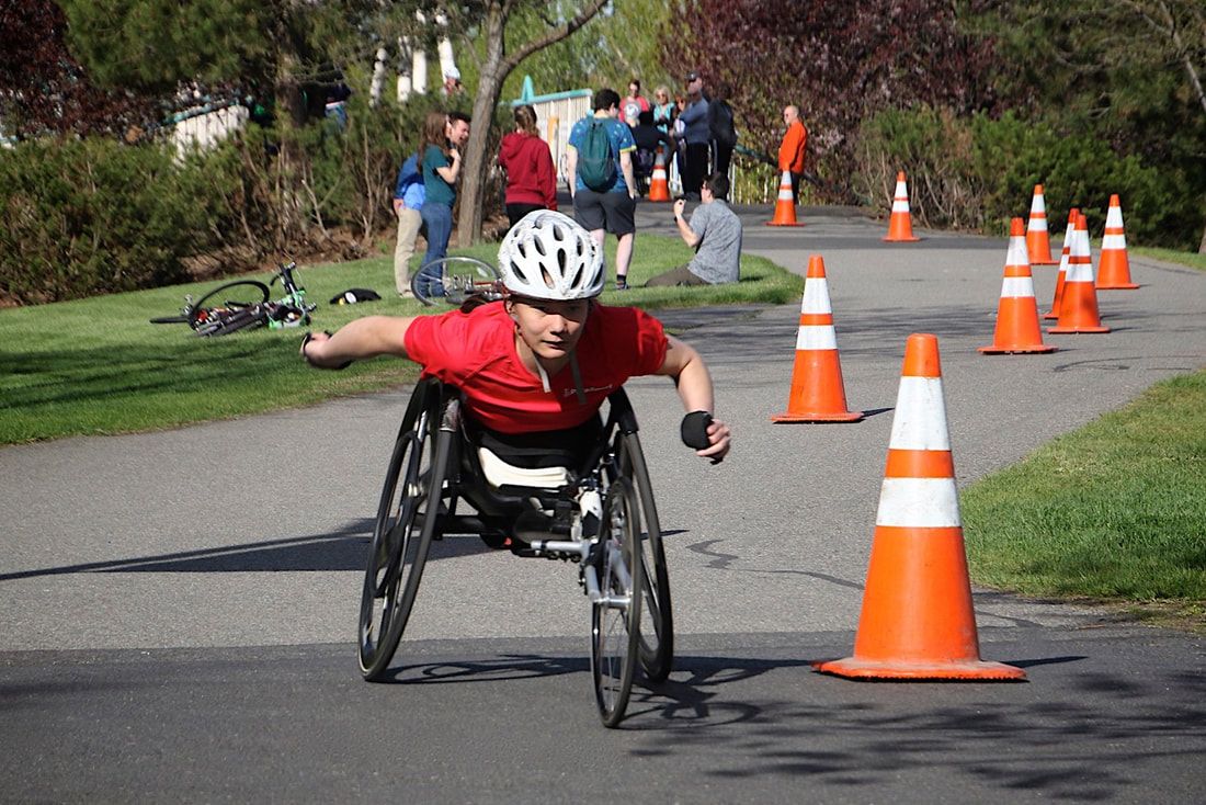 Racer in a red shirt and white helmet reaches forward between orange cones
