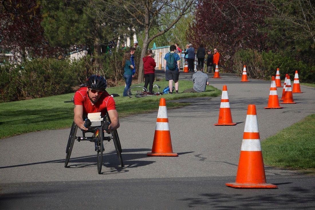Racer in a red shirt and sunglasses heads down a coned path toward the camera