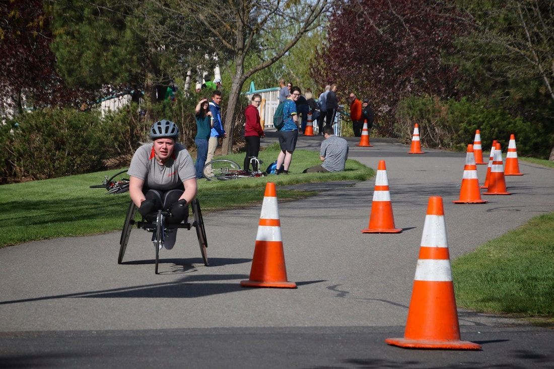 Racer in a gray shirt and helmet rolls through the cones as a crowd watches