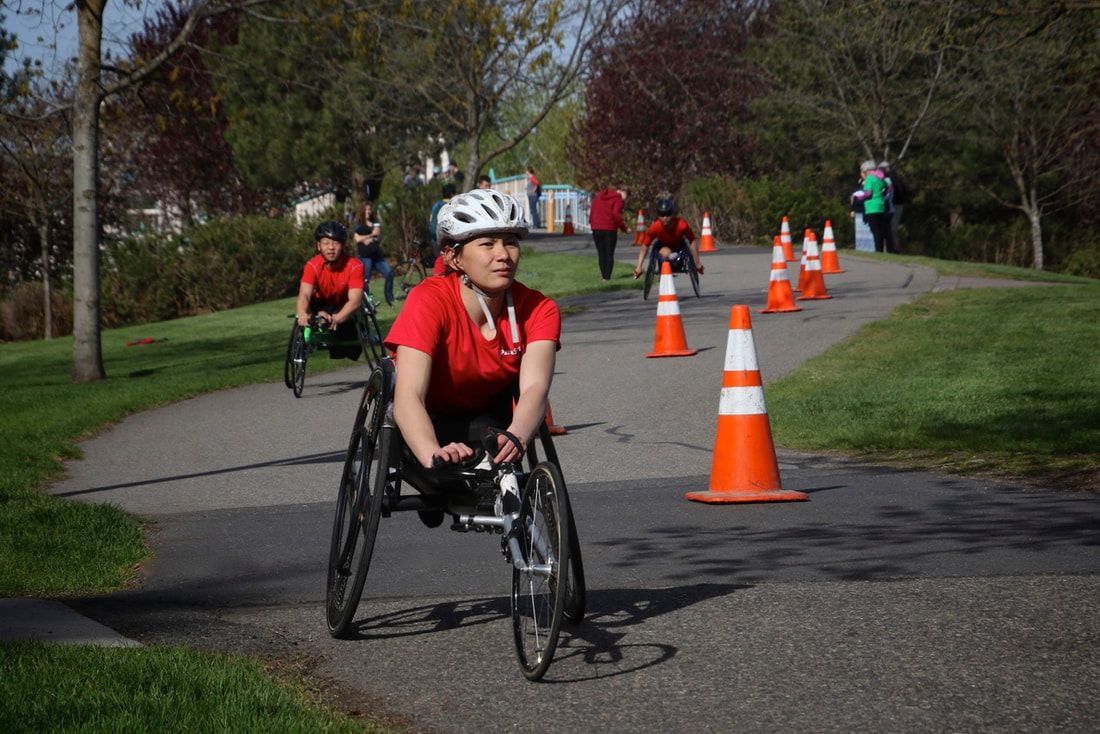 Racer in a red shirt and white helmet leads two others along a coned path